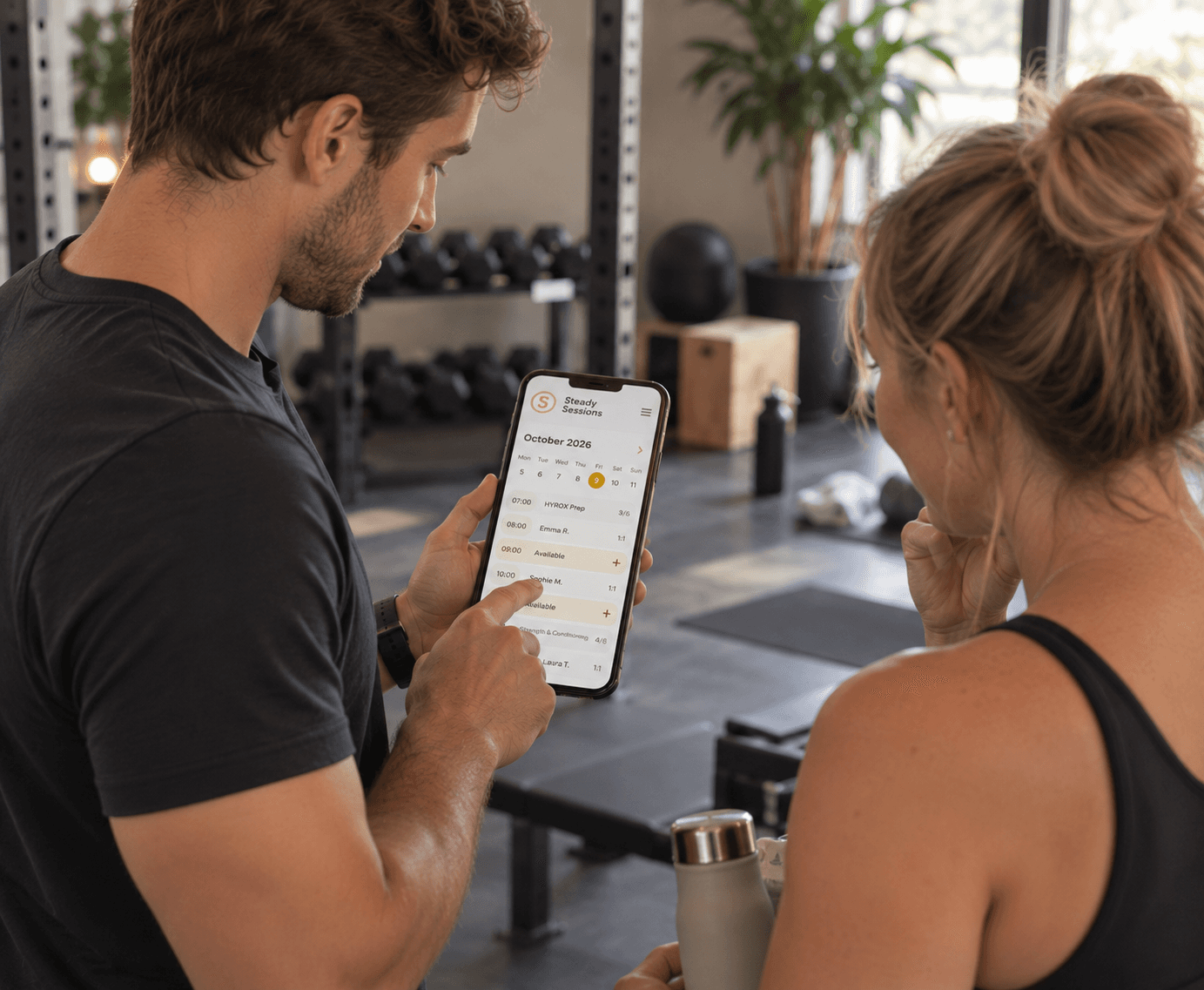 A personal trainer booking a client's next 1-to-1 on his phone in the gym